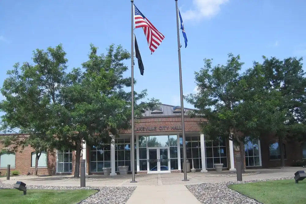 Lakeville City Hall entrance with flagpoles and shade trees in Lakeville, Minnesota