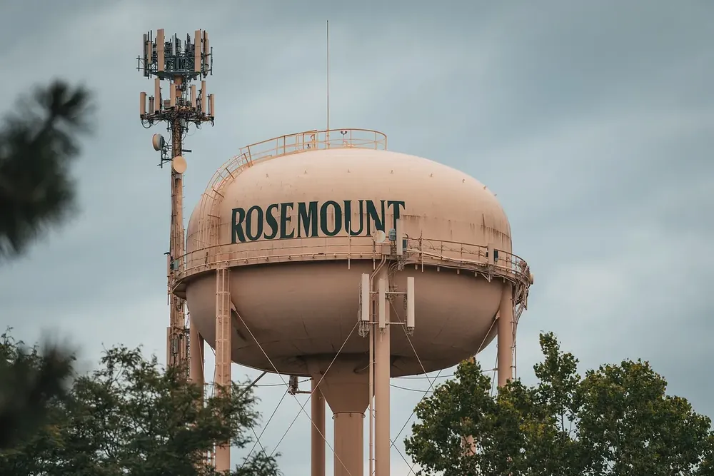 City water tower among summer trees under a cloudy sky in Rosemount, Minnesota
